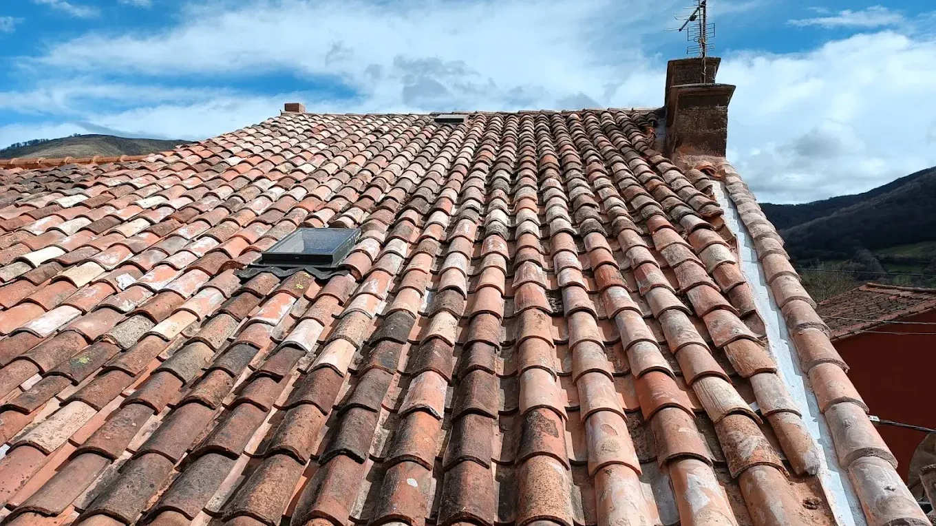Tejado de teja árabe con ventana de tejado y el remate lateral junto a la pared recién sellado